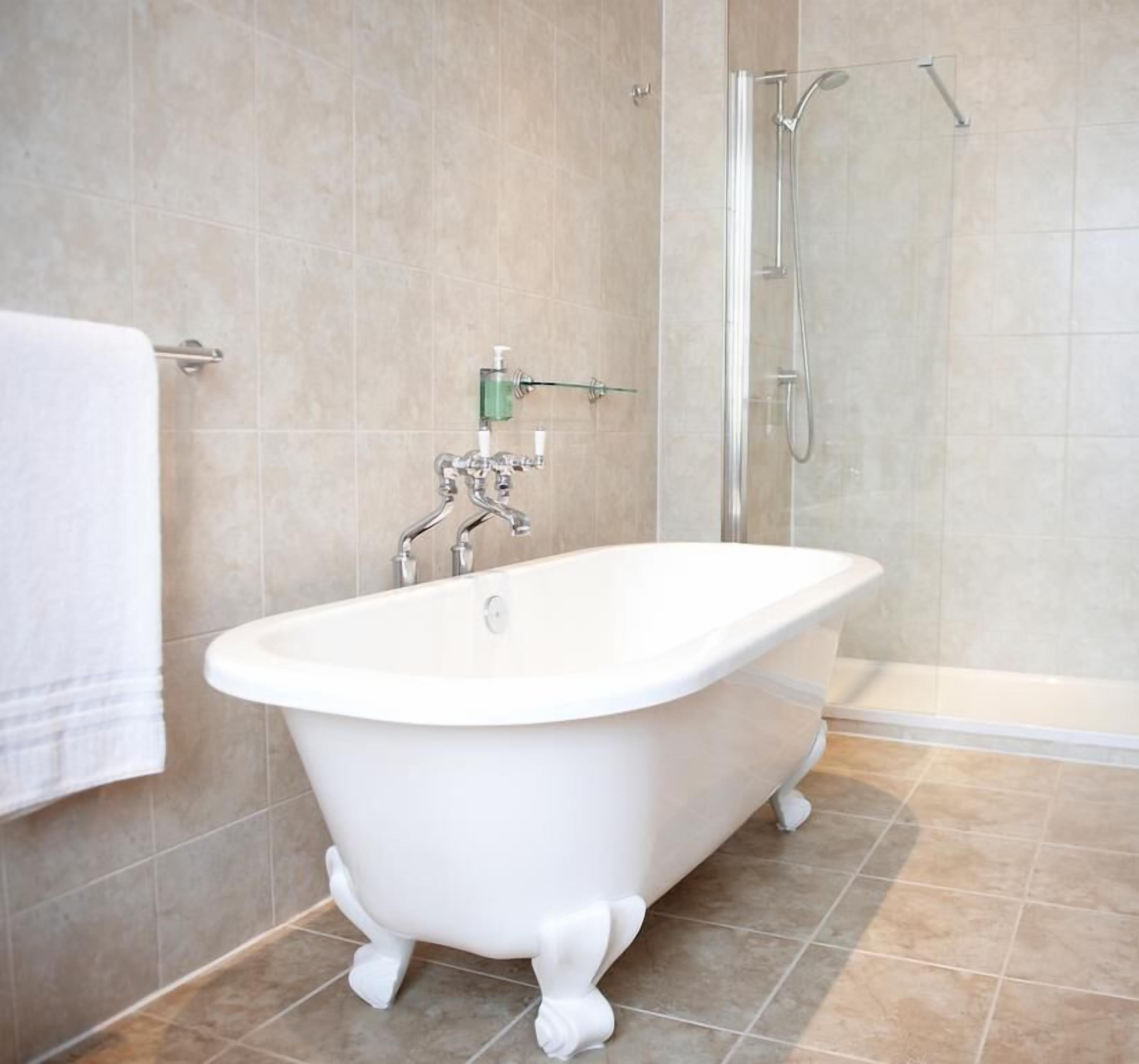 A bathroom with a freestanding bathtub, a glass shower enclosure, and a towel rack.