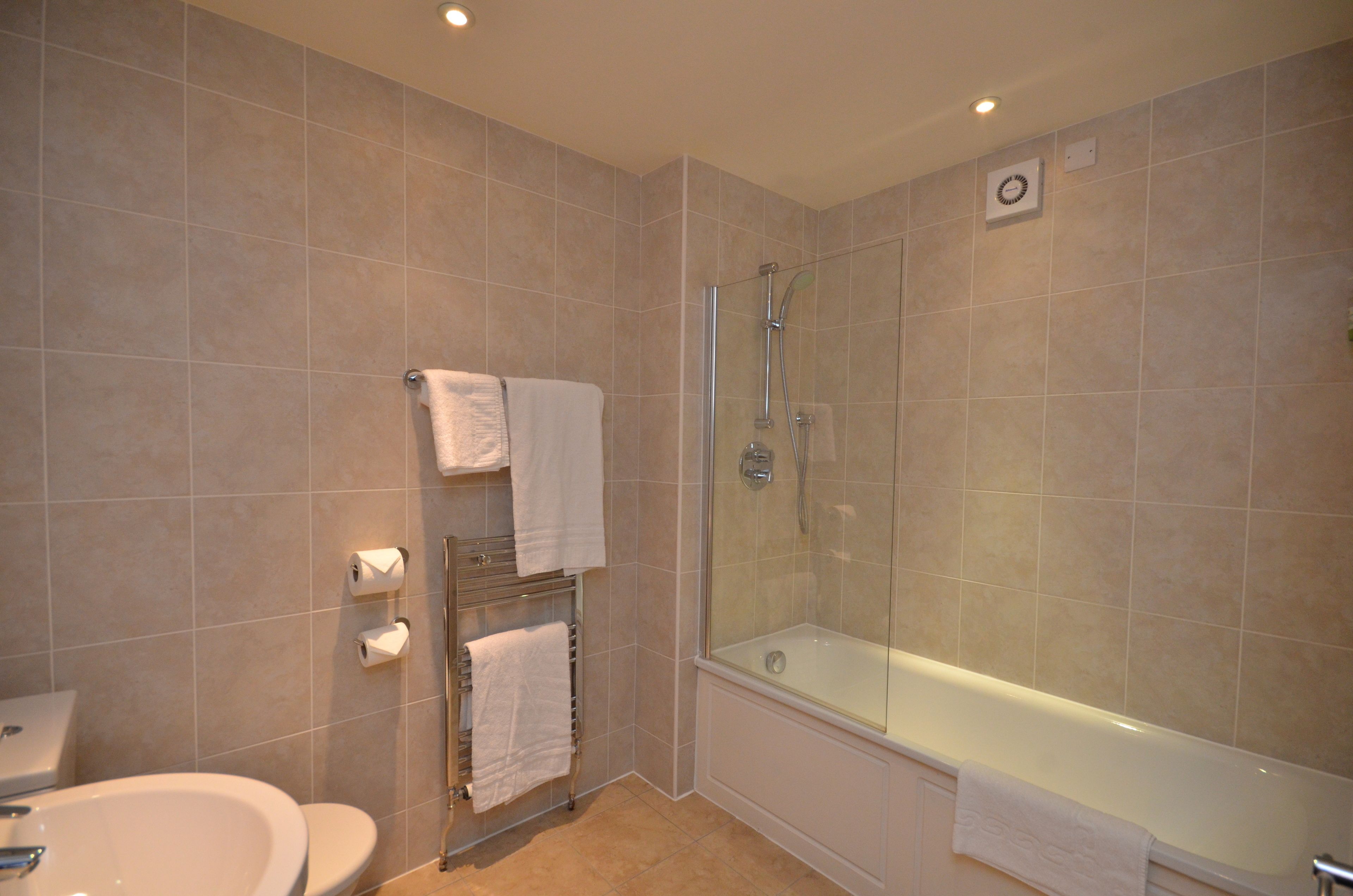 A modern bathroom with a glass-enclosed shower, a bathtub, and a toilet.