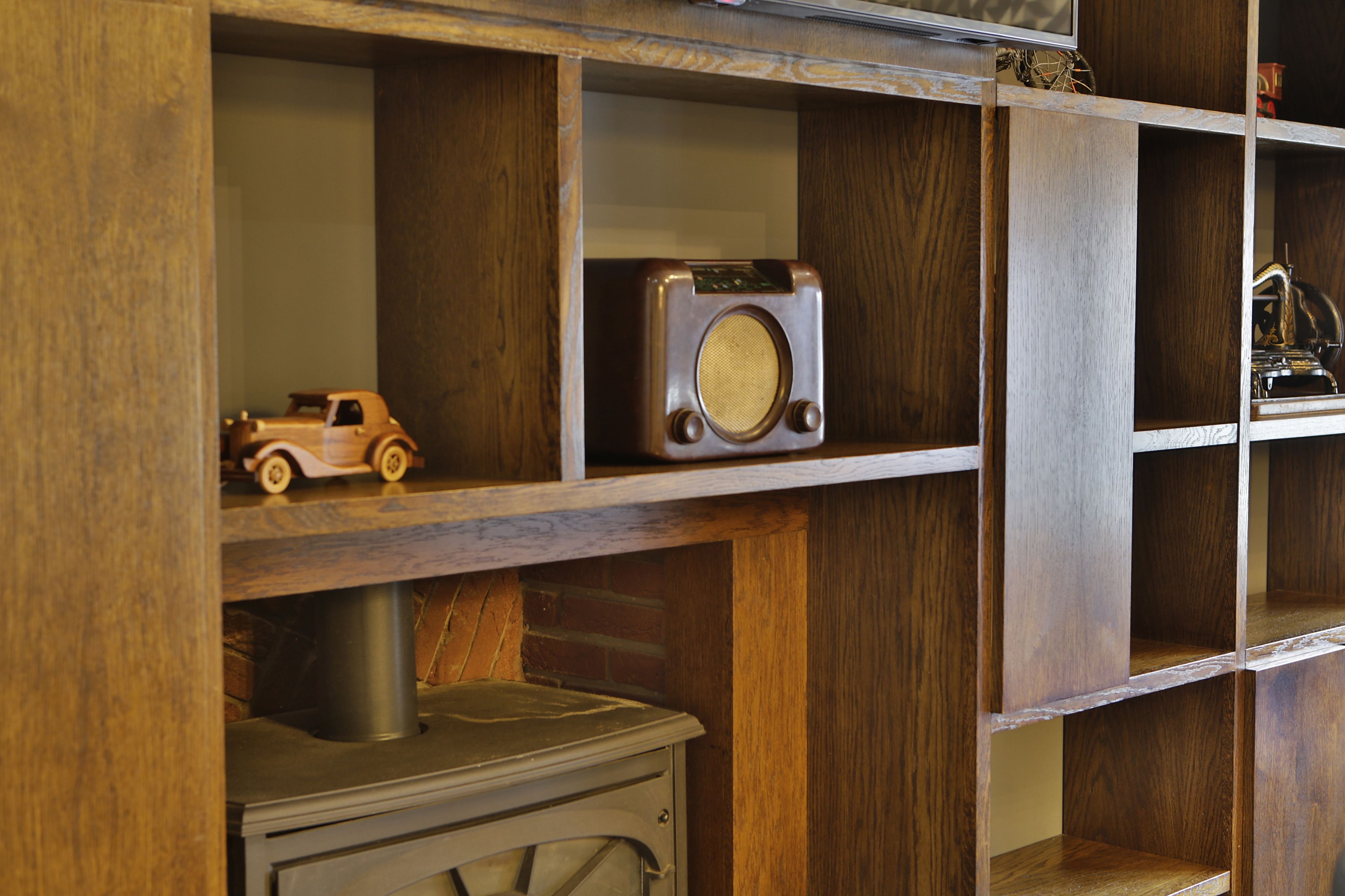 A wooden shelf unit with various items including a vintage radio, a toy car, and a small mechanical device.