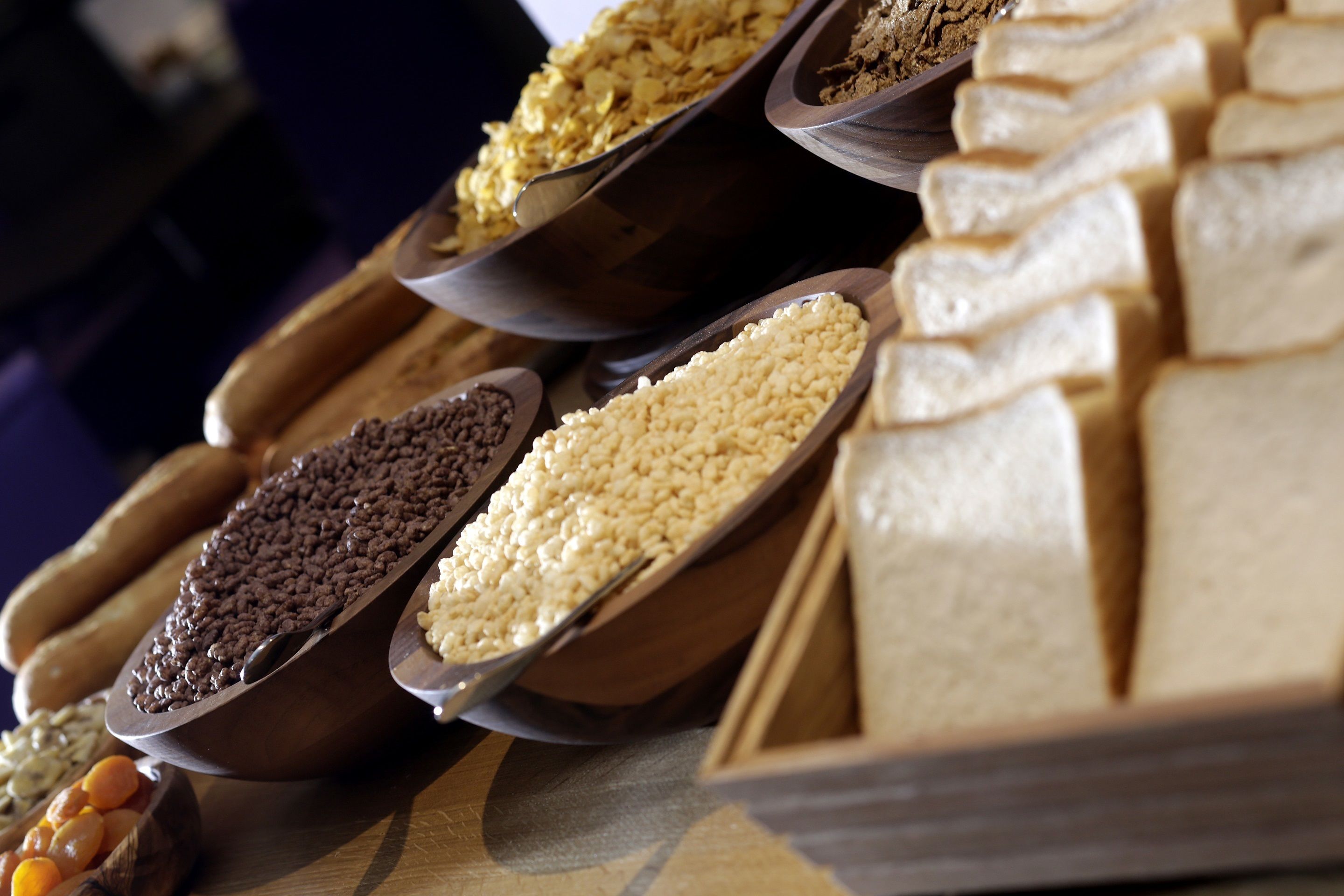 A variety of grains and seeds displayed in wooden bowls and spoons.