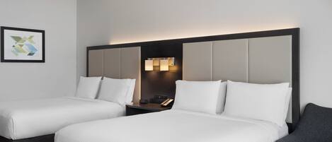 A hotel room with two beds, a nightstand, a lamp, and a framed picture on the wall.