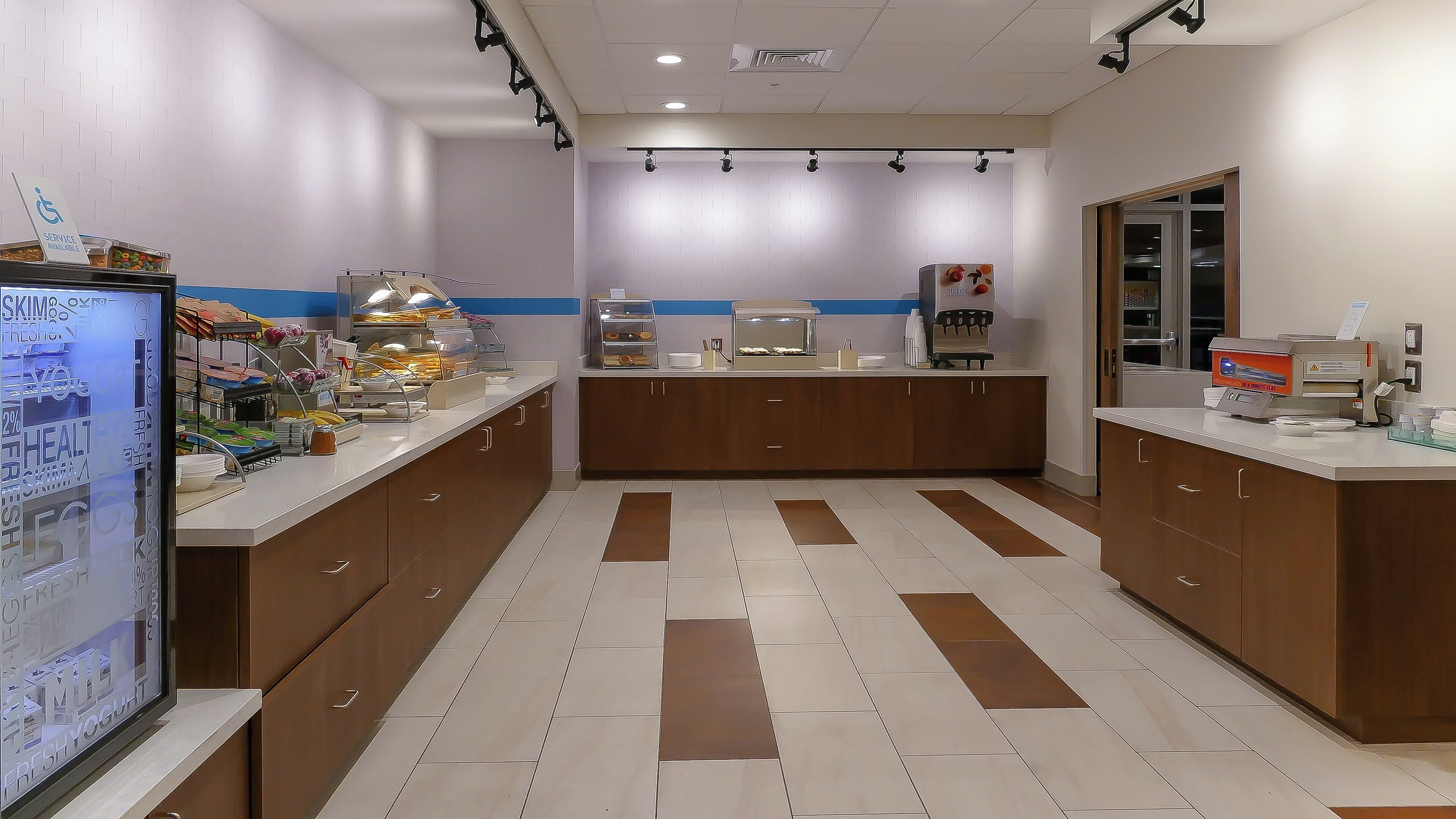 A clean, well-lit cafe with a counter, seating area, and a display of food items.