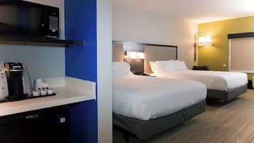 A hotel room with two beds, a minibar, a coffee maker, and a television.
