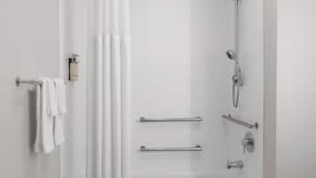 Un baño moderno con bañera, ducha y barras de apoyo.