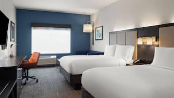 Una habitación de hotel con dos camas, un escritorio, una silla y un ventanal grande.
