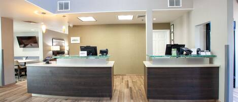 A reception area with two counters, a flat-screen TV, and a seating area with a table and chairs.