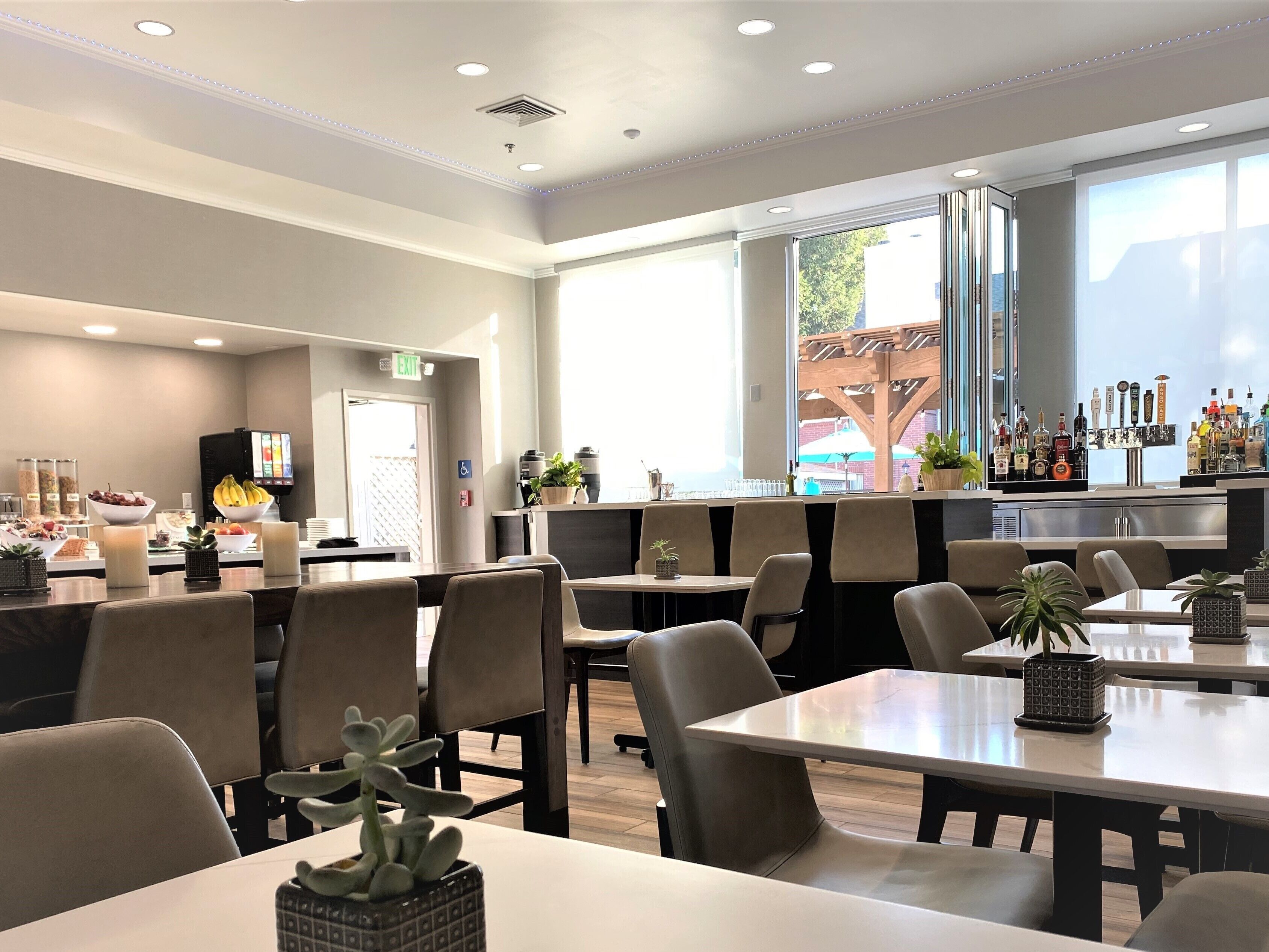 A modern restaurant with a bar area, seating, and a buffet.