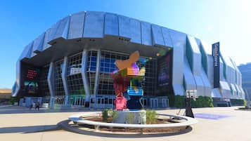 Un estadio moderno con un diseño arquitectónico único, que presenta una gran pantalla digital mostrando información del evento.