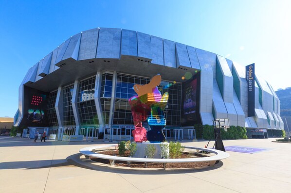 A modern stadium with a unique architectural design, featuring a large digital screen displaying event information.