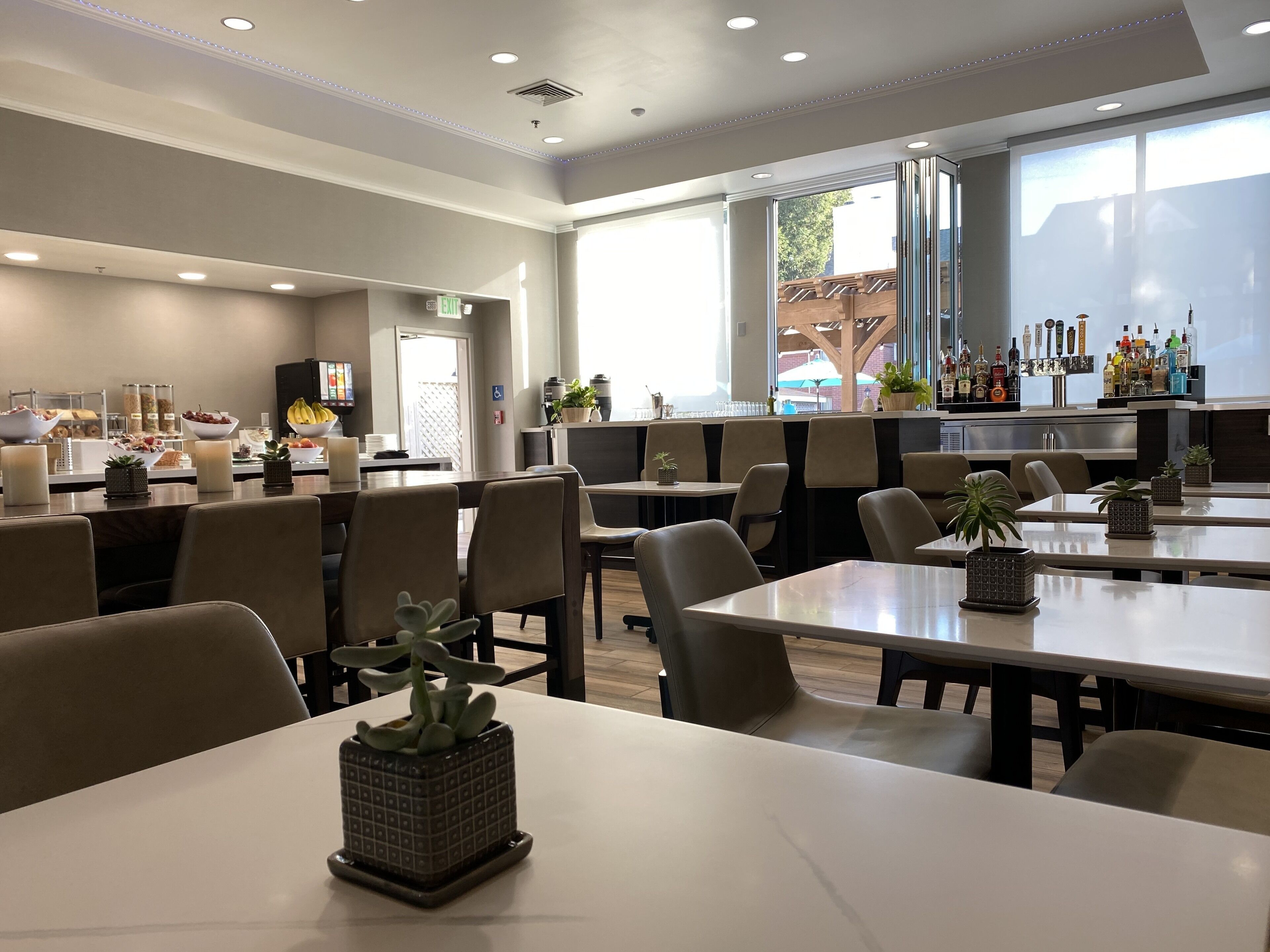 A modern restaurant with a bar area, seating, and a view of the outside.