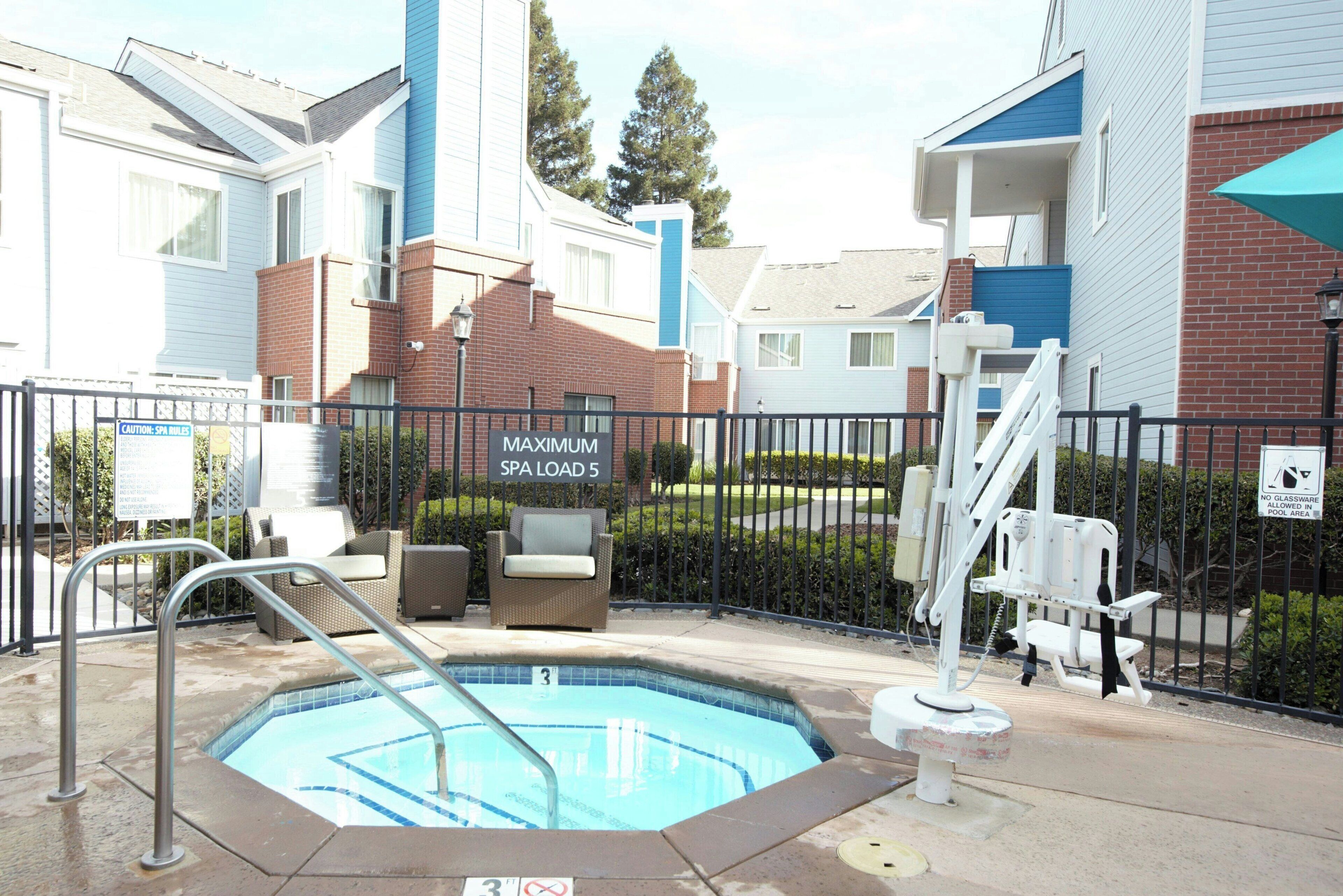 Zona de piscina con un cartel que indica un aforo máximo de 5 personas en el spa.