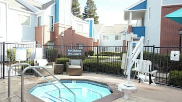 Zona de piscina con un cartel que indica un aforo máximo de 5 personas en el spa.