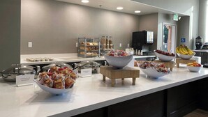 Un espace buffet proposant une variété d’aliments, notamment des bols de collations, des fruits et des récipients étiquetés contenant différents plats.
