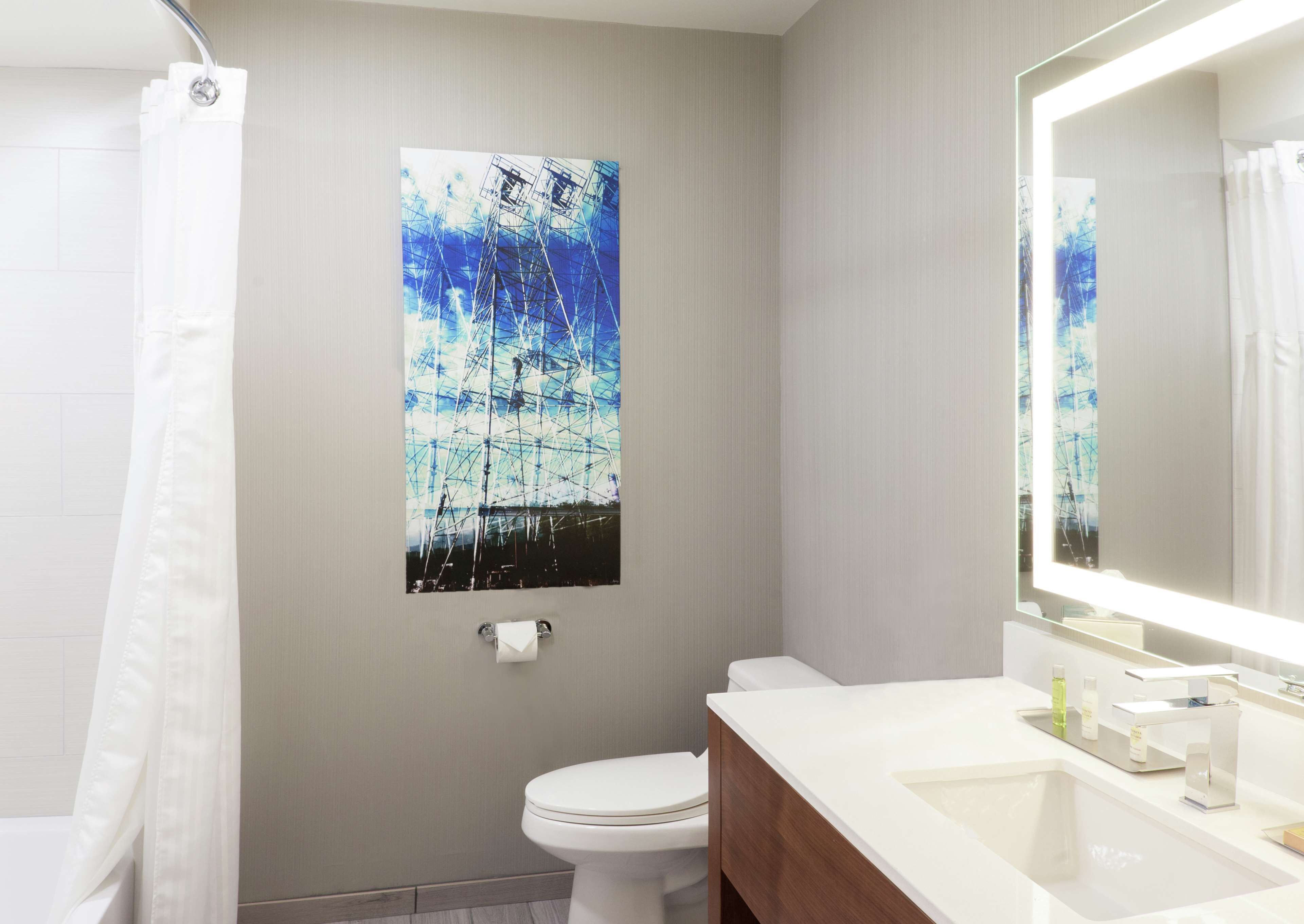 Un baño con inodoro, lavamanos, espejo y cortina de ducha.