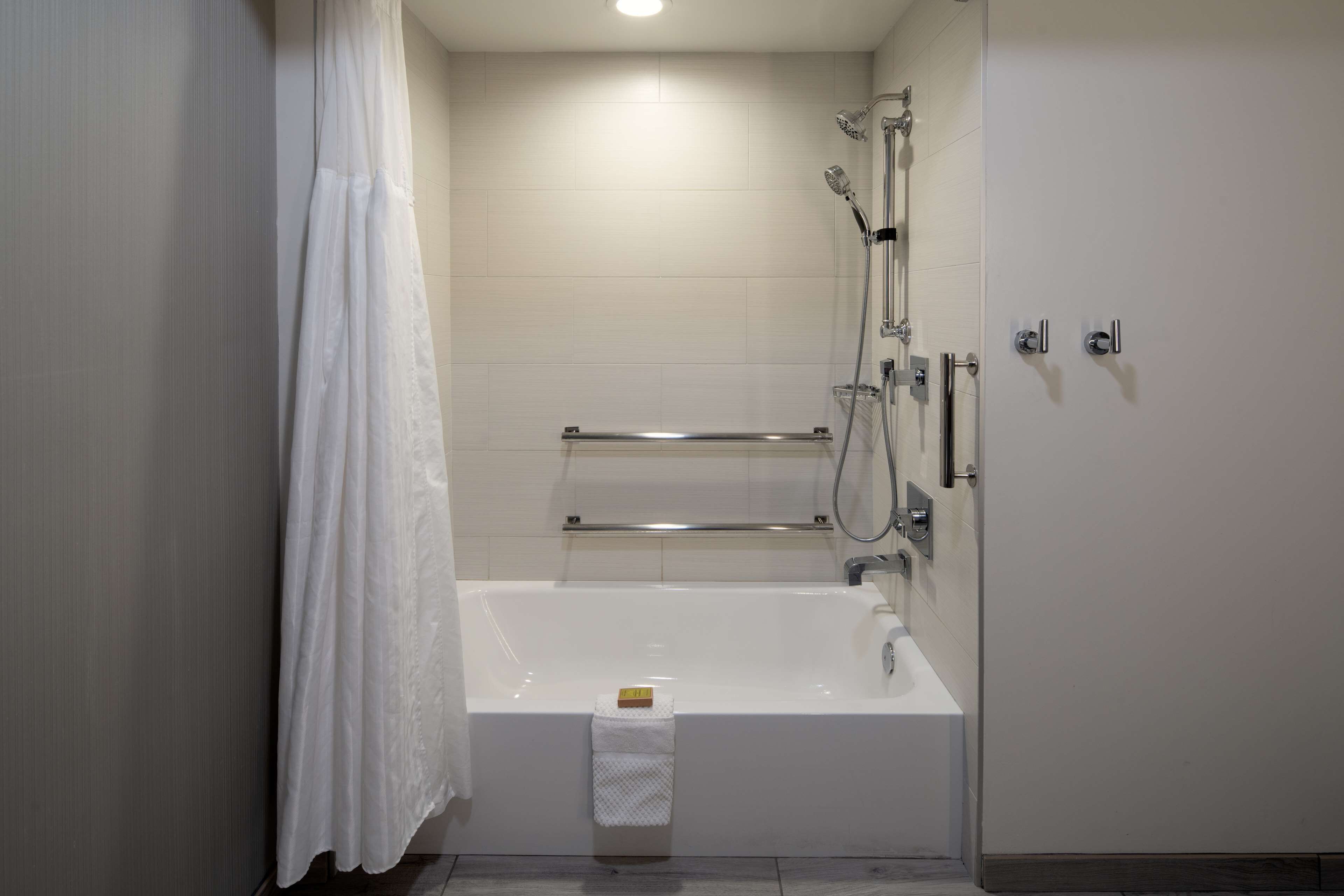 Un baño moderno con bañera, ducha y barras de apoyo.