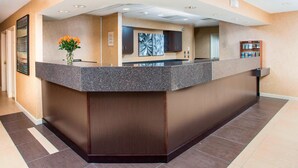 A reception area with a marble counter, a vase of flowers, and a large abstract painting on the wall.