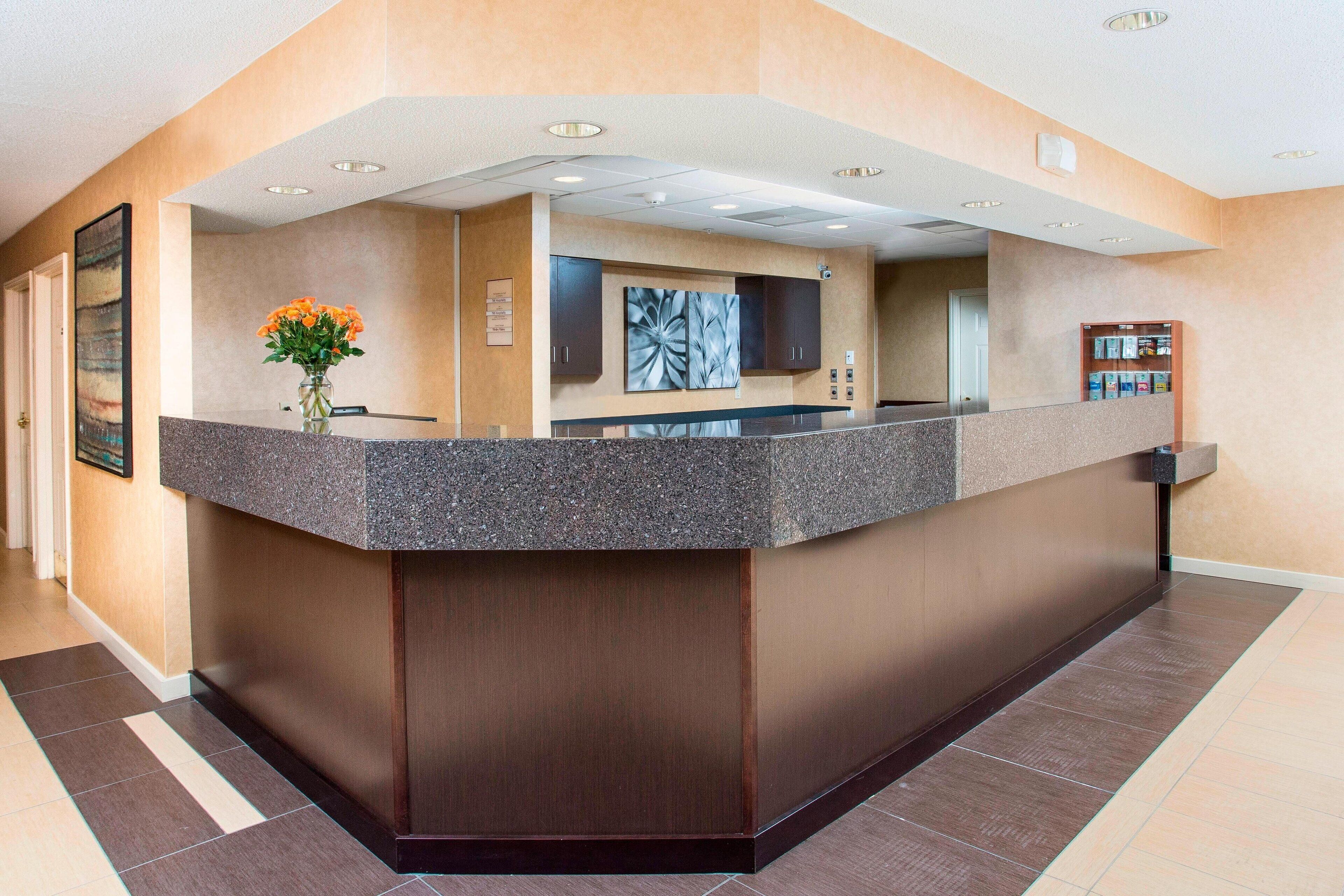 A reception area with a marble counter, a vase of flowers, and a large abstract painting on the wall.