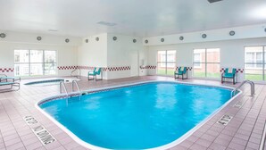 A swimming pool with a no diving sign, surrounded by chairs and a tiled floor.