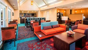 A hotel lobby with a seating area, a reception desk, and a kitchen in the background. - Residence Inn by Marriott Topeka (Topeka)