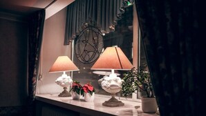 A window with two table lamps, a decorative wall piece, and potted plants on a window sill. - Hotel Anna (Helsinki)