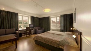 A hotel room with a bed, a sofa, a desk, and a chair. - Hotel Anna (Helsinki)