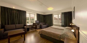 A hotel room with a bed, a sofa, a desk, and a chair.
