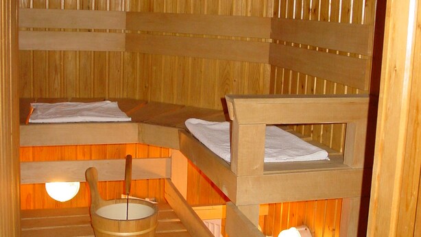 Una sauna de madera con bancos y un balde de madera.