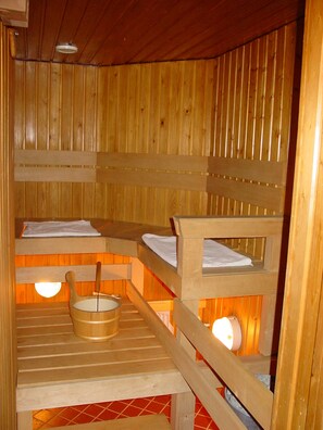 A wooden sauna with benches and a wooden bucket.