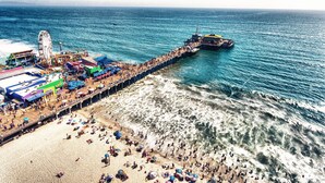 An aerial view of a beach with a pier, a Ferris wheel, and a shipwreck. - Hotel Carmel (Santa Monica)