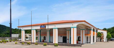 A Howard Johnson motel with a red roof and white facade, featuring a covered parking area and a signboard.