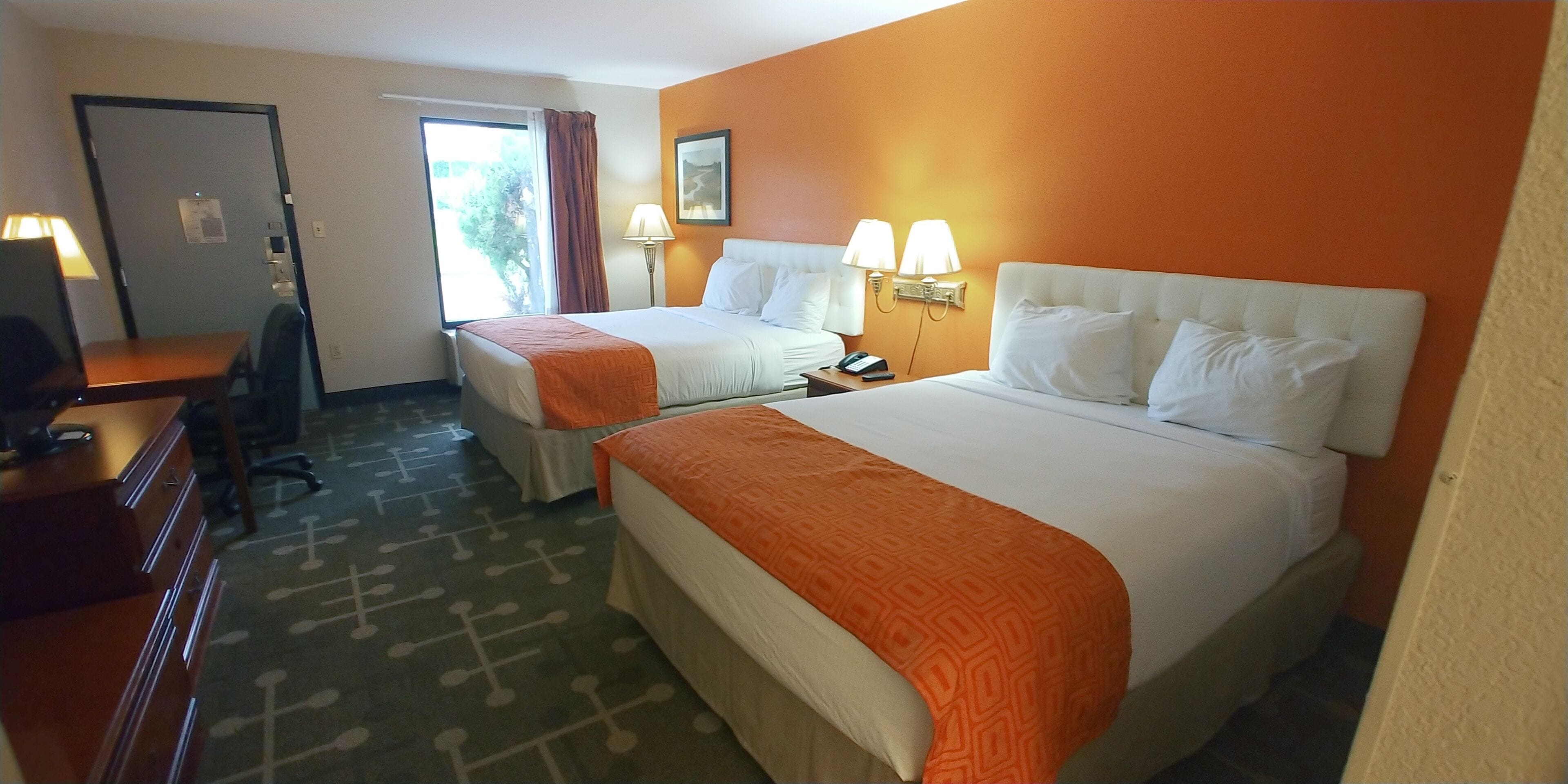 Ein Hotelzimmer mit zwei Betten, einem Schreibtisch und einem Stuhl.
