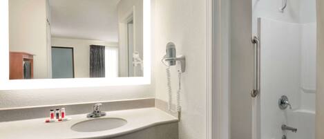 A bathroom with a sink, mirror, and a shower.