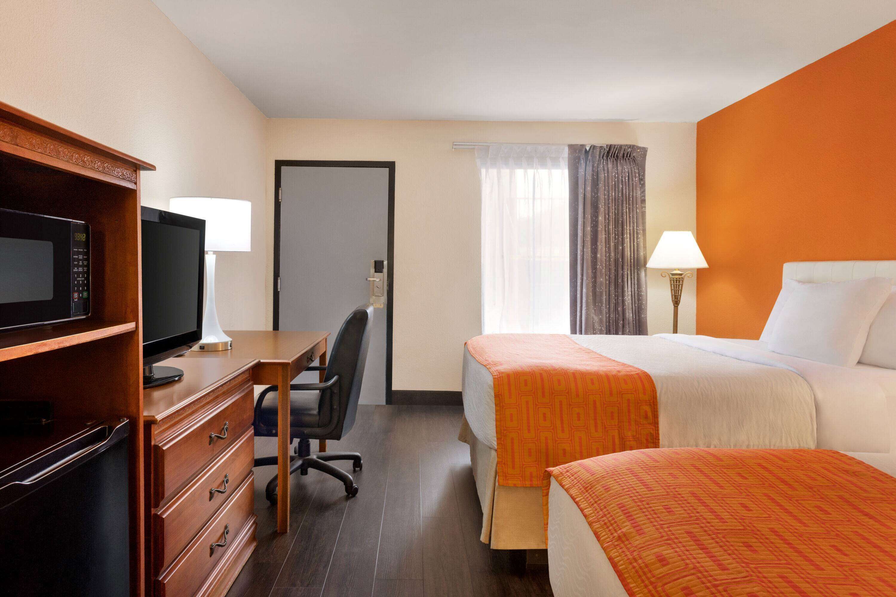 A hotel room with a bed, a desk with a computer, a television, and a wardrobe.