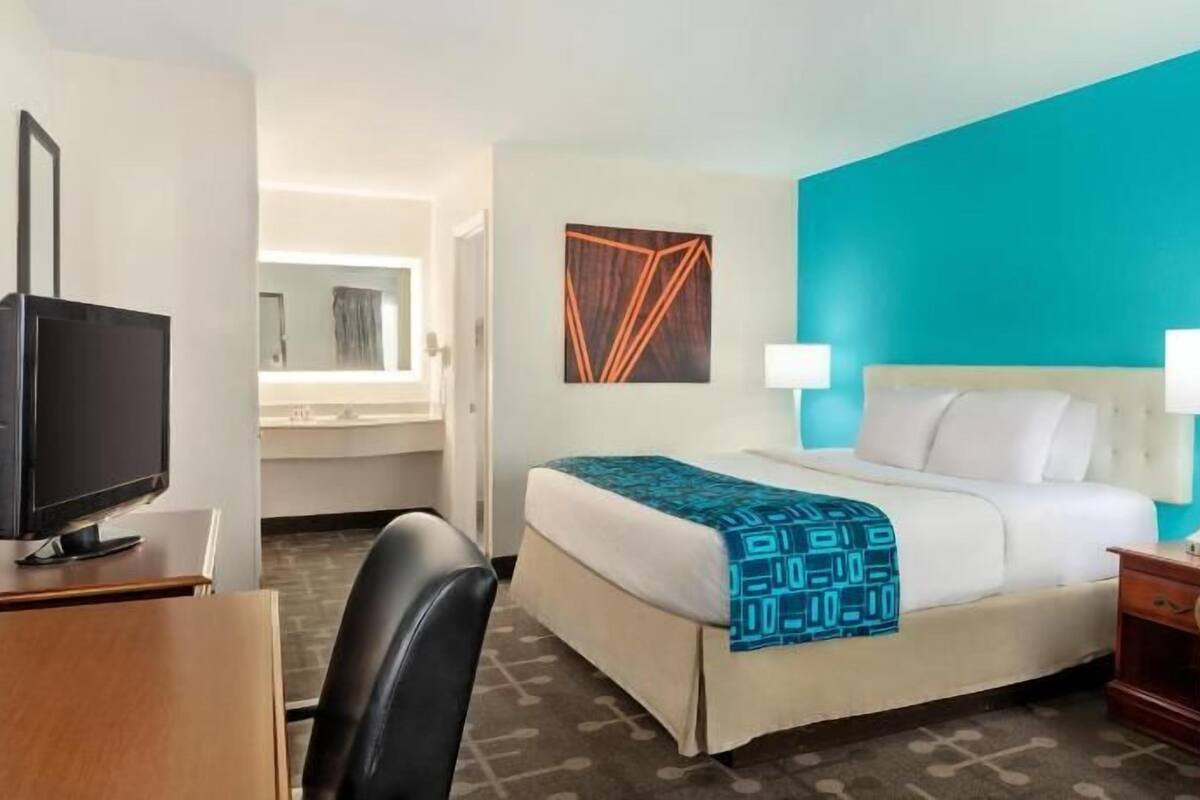 Een hotelkamer met een bed, twee bedlampen, een televisie, een bureau en een stoel.