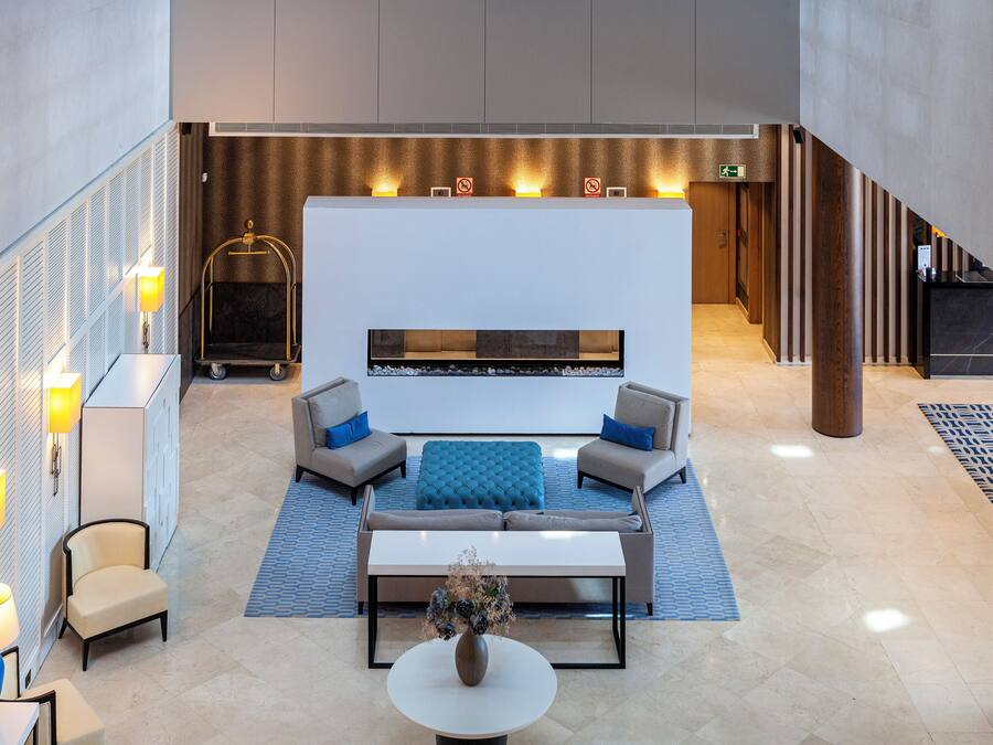 Un lobby moderno con zona de estar, mostrador de recepción y escalera.