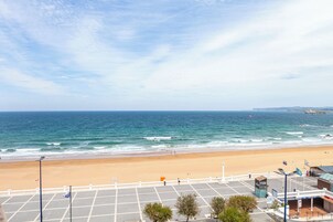Vista de la playa con un estacionamiento, un edificio con un letrero y un asta de bandera.