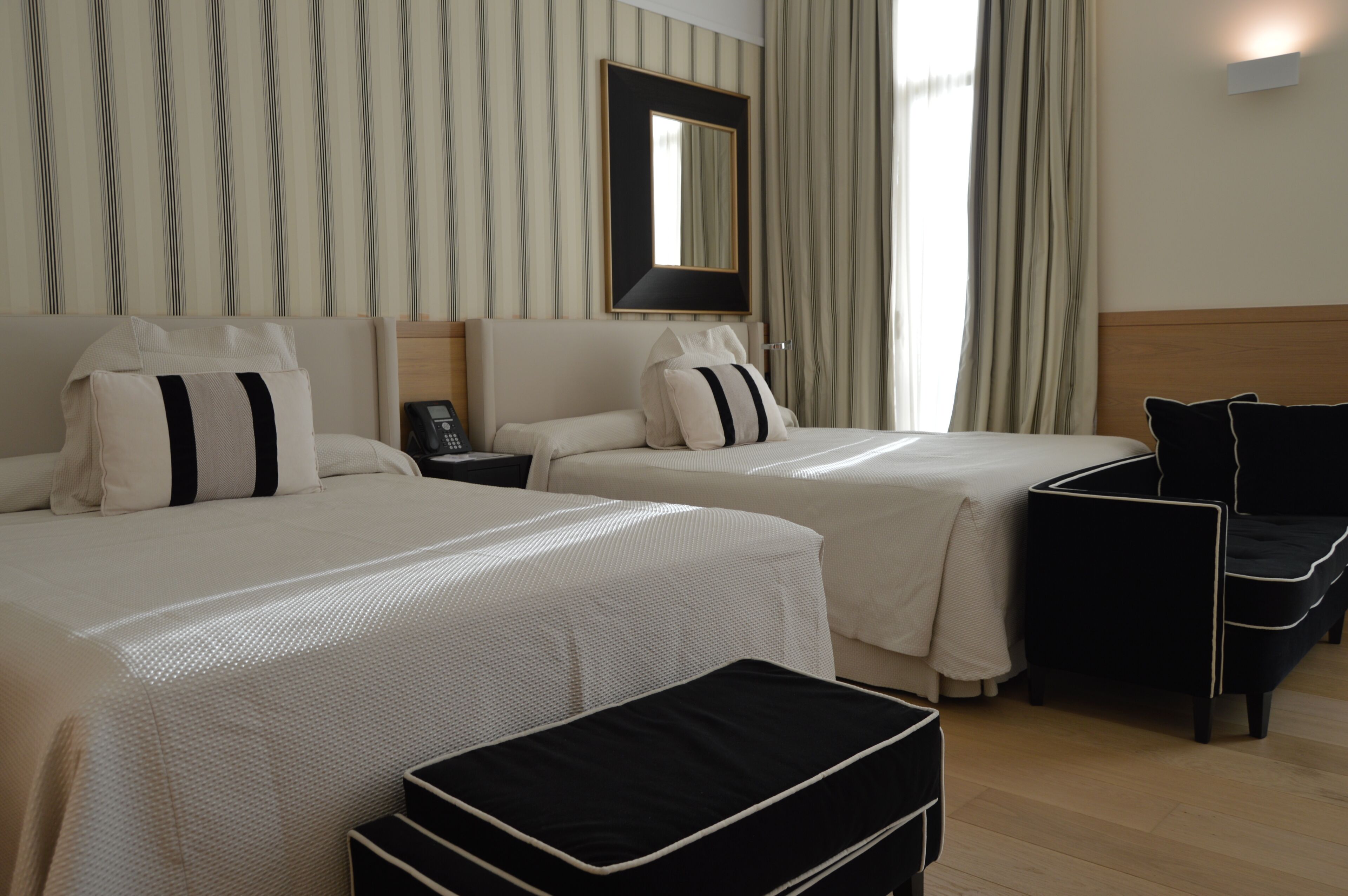 A hotel room with two beds, a nightstand, a desk, and a chair.