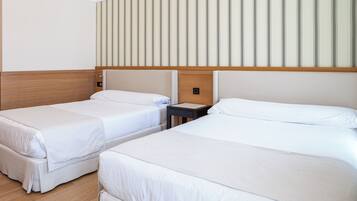 A hotel room with two single beds, a wooden headboard, a striped wall, and a small bedside table.