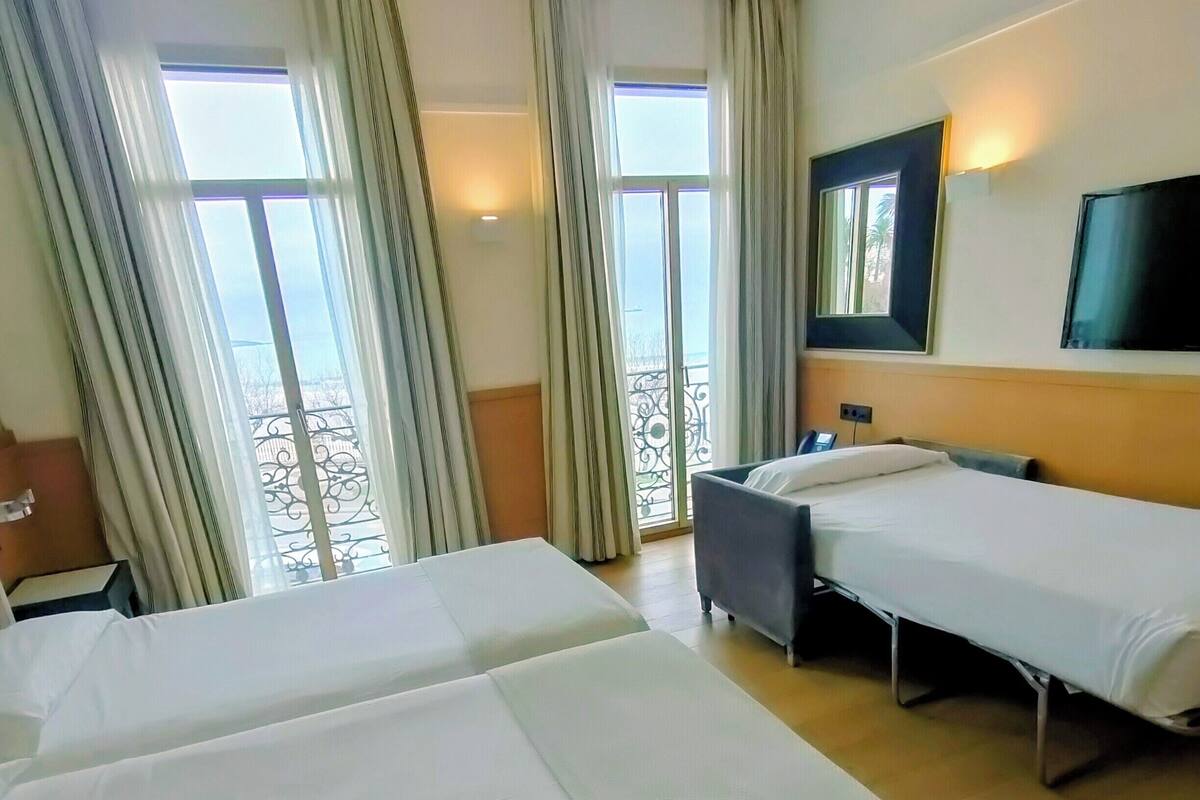A hotel room with two beds, a desk, and a TV.