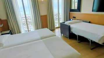 A hotel room with two beds, a desk, and a TV.