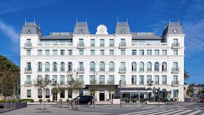 A large, white hotel with a central clock tower and two smaller towers on either side.