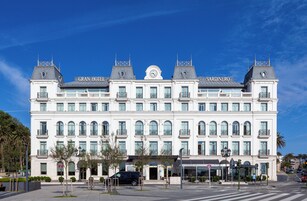 Un hotel grande y blanco, con una torre central de reloj y dos torres más pequeñas a cada lado.