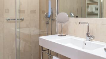 Un baño moderno con ducha acristalada, lavamanos blanco y espejo.