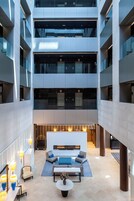 Un atrio de varios niveles con una zona de estar central, ventanas amplias y mobiliario moderno.