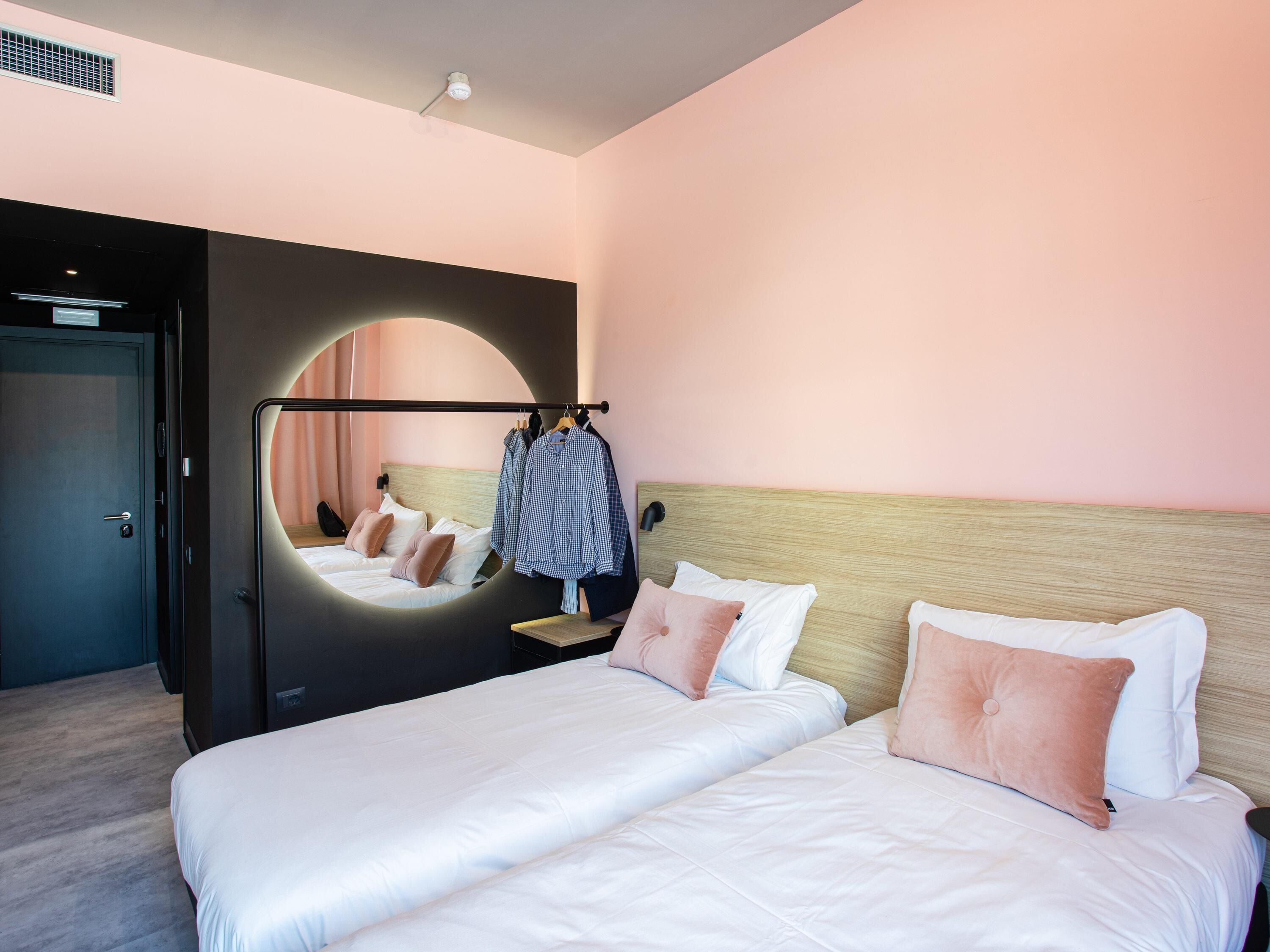 Una habitación de hotel con una cama grande, un espejo y un armario.