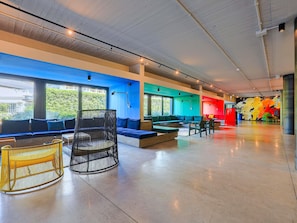 A modern lounge area with seating, a round wicker chair, and a colorful mural. - ibis Styles Roma Aurelia (Rome)