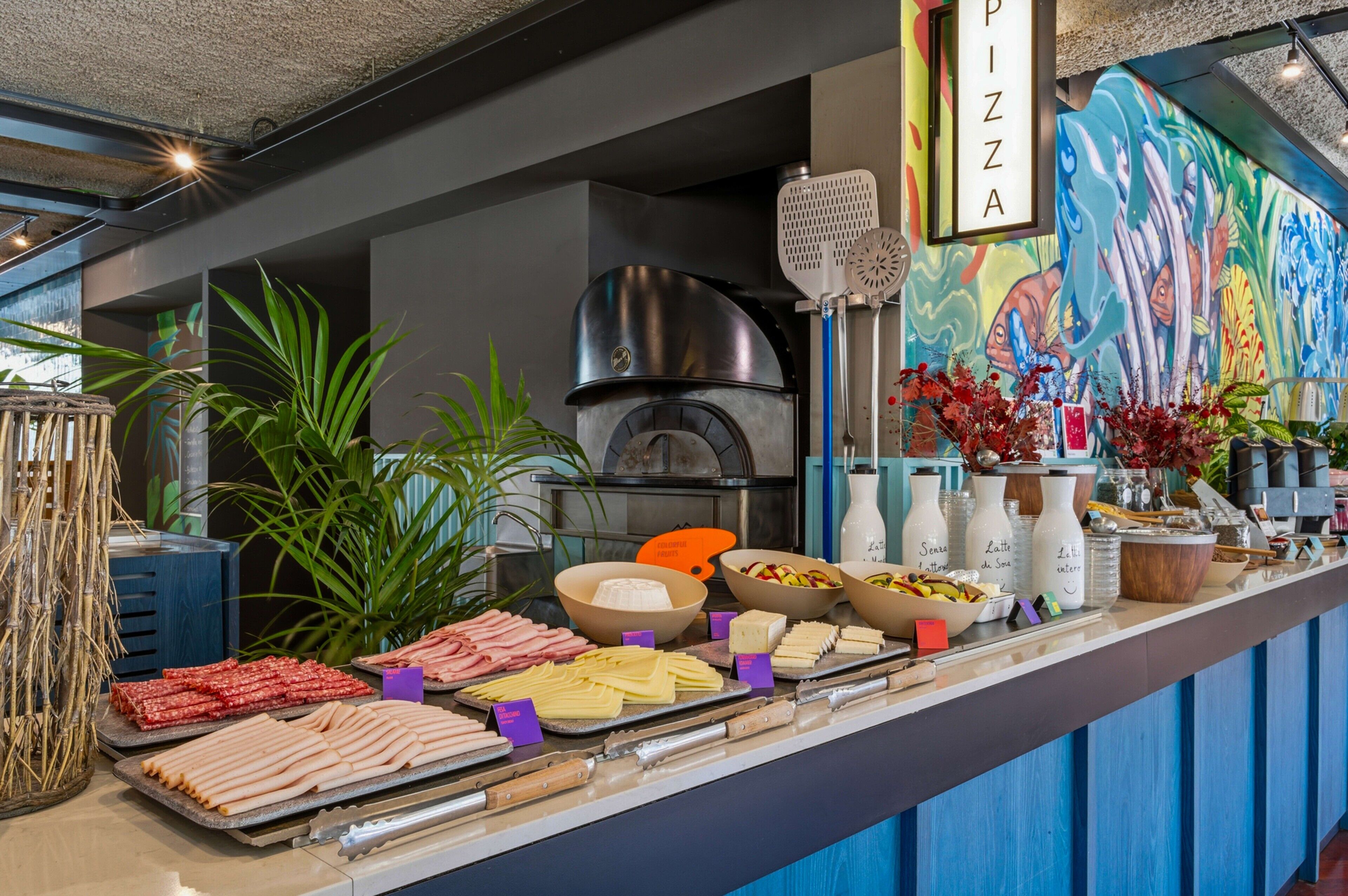 Een buffet met diverse gerechten, een pizza-hoek en een muurschildering.