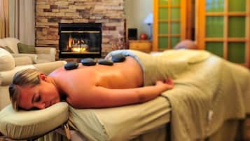 Experience a soothing massage in a peaceful space with a fireplace, comfortable couch, and dedicated massage table.