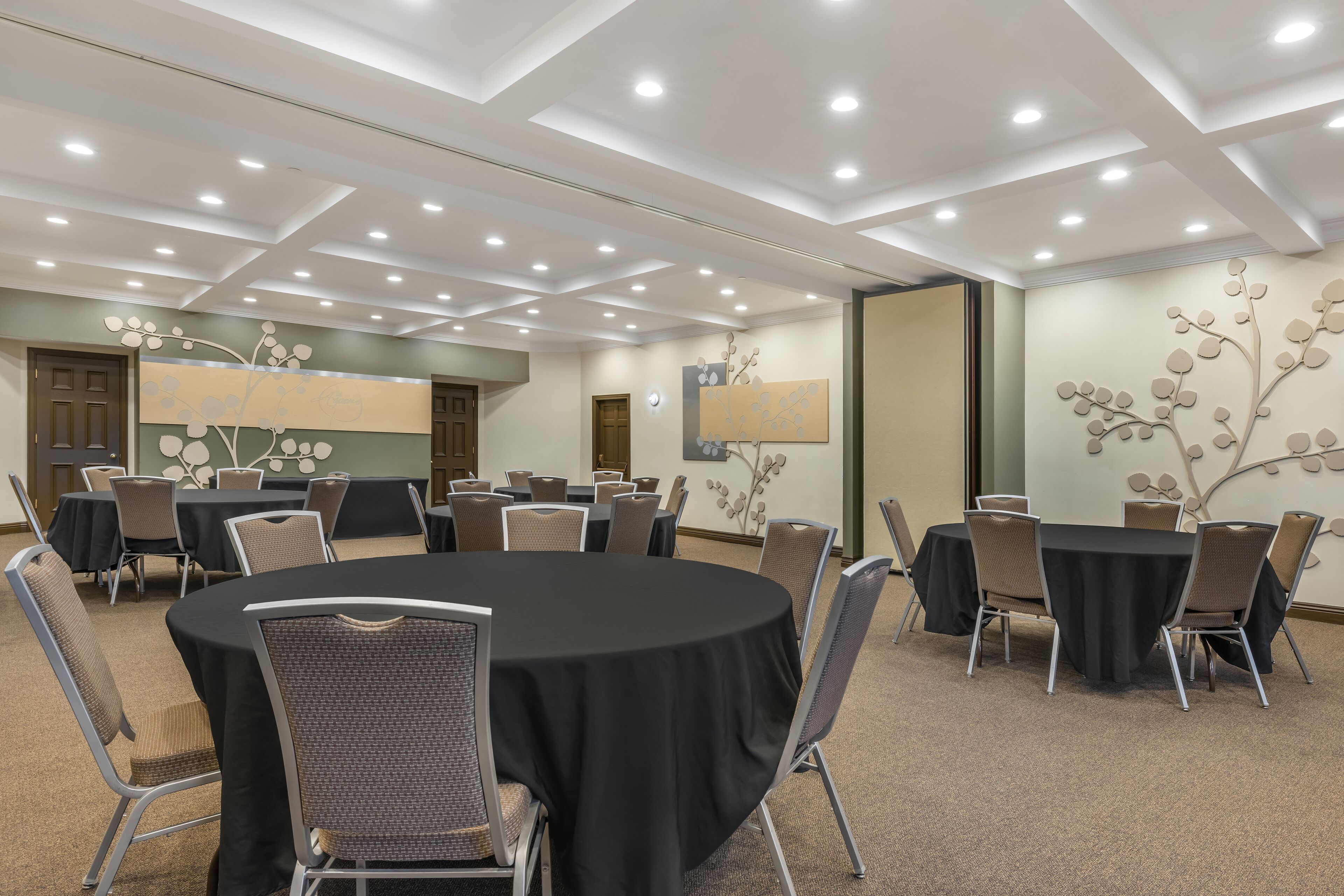 Een vergaderzaal met ronde tafels, stoelen en inbouwverlichting.