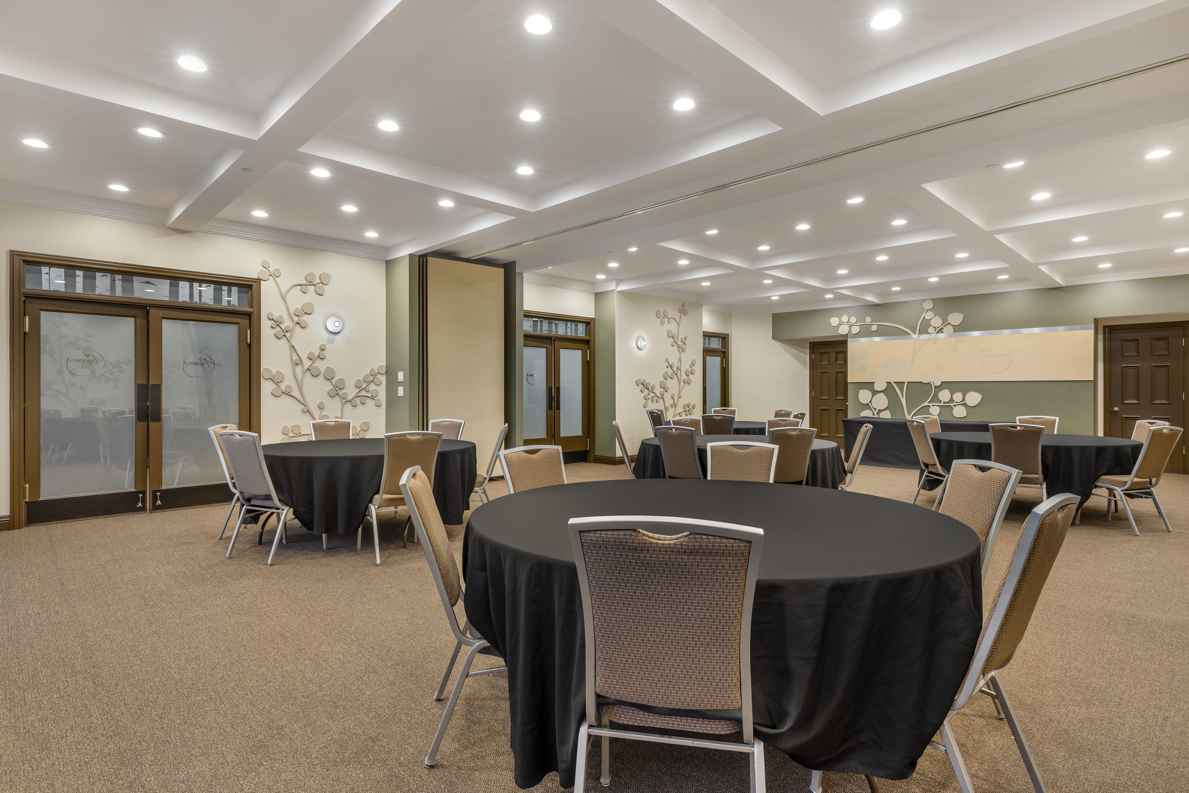 A conference room with round tables, chairs, and a ceiling with recessed lighting.
